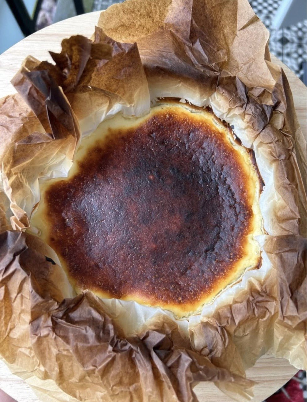 Freshly baked Basque burnt cheesecake in parchment paper on a wooden board